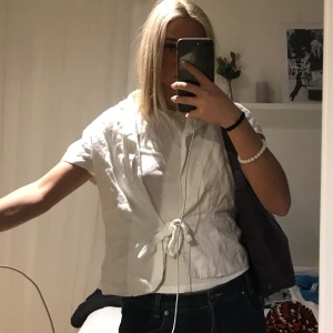 Vit blus - Cool blus med knytning köpt second hand. Väldigt skrynklig men kan såklart stryka den innan jag skickar iväg om så önskas! Storlek 36 i linne material