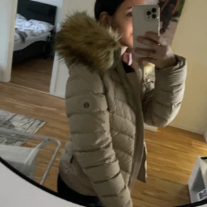 Hollies jacka beige  - Fin hollies jacka beige använts en vinter och inte mer, inget fel på jackan (fake päls) 