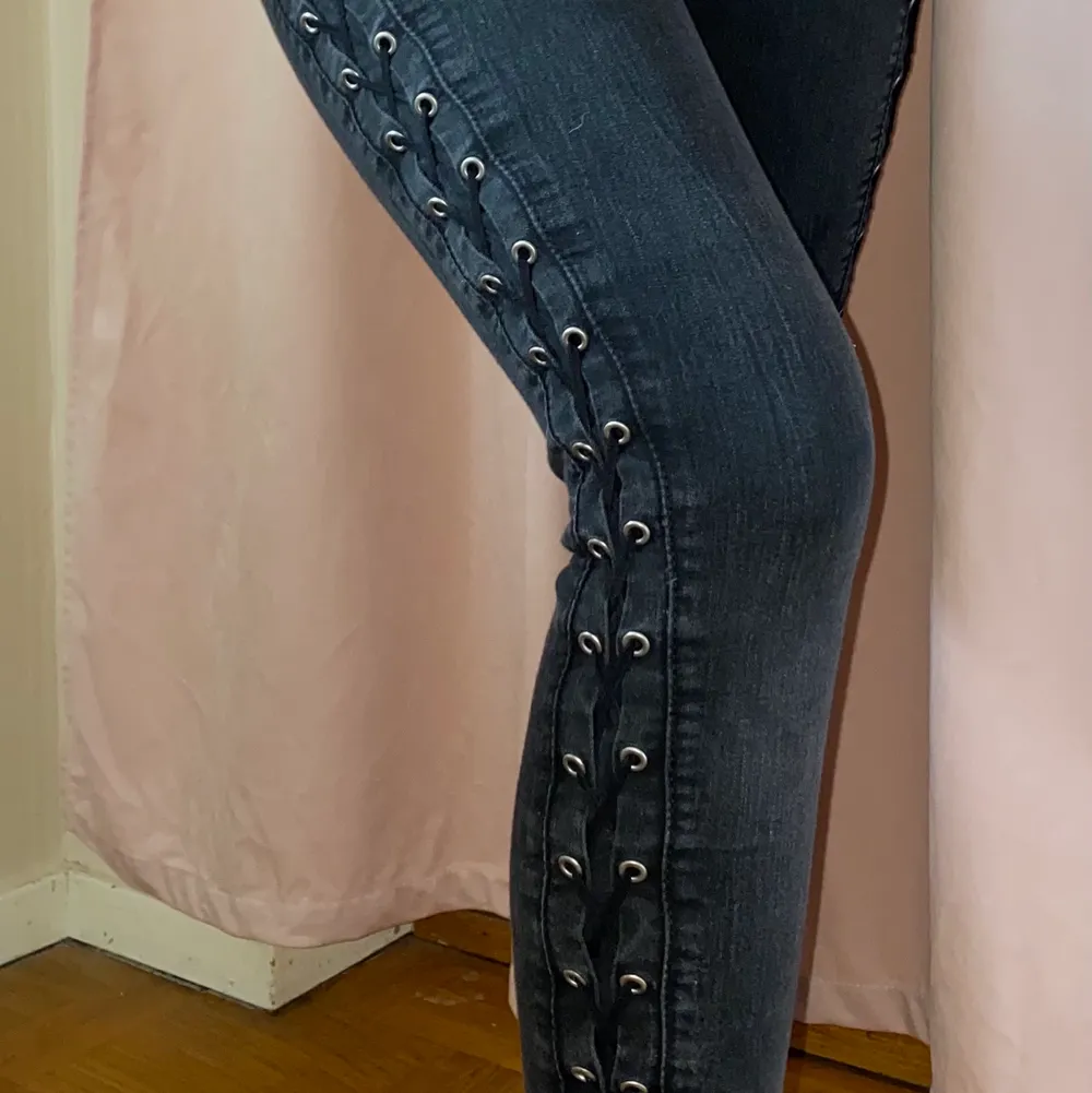 Grå svarta jeans med korsad snörning längs med sidorna av benen och höfterna, storlek 34. Jeans & Byxor.