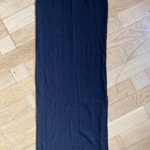 Svart tubkjol från Ginatricot  - Svart ribbad tubkjol från Ginatricot. Har en split på ena sidan och slutar en bit under knäna. Resor i midjan. 