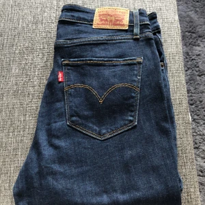 Jeans från Levis - Mörkblåa jeans från Levis. Hög midja. Använda 3 gånger. Storlek 28. Står enbart storlek 28 i jeansen men skulle gissa på en längd 32. Katt finns i hemmet. 