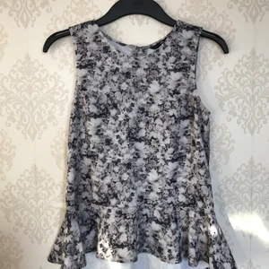 Peplum top H&M - Fin gråblommig peplumtop i nyskick. Blixtlås på baksidan 