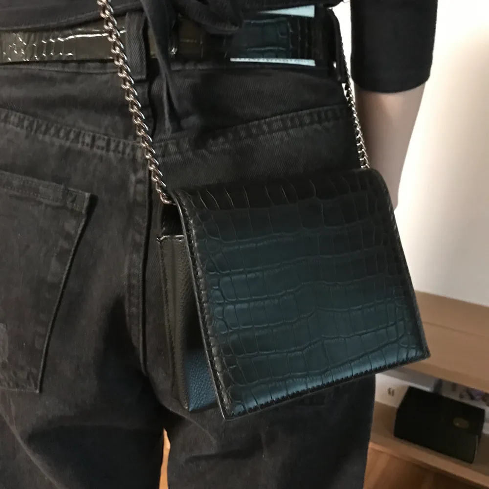 Nypris 249 kr. “Croco Mini Messenger Bag” Den här väskan från NA-KD Accessories har ett huvudfack med en tryckknappsstängning, en innerficka med en dragkedjestängning, en justerbar kejdehandtag och en ormimitation. This bag comes in black. Height: ca. 12 cm / 4.7 in. Width: ca. 3 cm / 1.2 in. Length: ca. 14 cm / 5.5 in. Material: Outer Shell: 100% Polyurethane. Lining: 100% Polyester. Brand new item, JUST without tags. Comes with dust bag. Never used and only tried on for two minutes. Only handled when I took the pic, the rest of the time was in my closet. Happy to bundle. Will gladly take more pics. Smoke and pet free storage space. No other flaws to note.    **TRACKED SHIPPING VIA POSTNORD** . Väskor.
