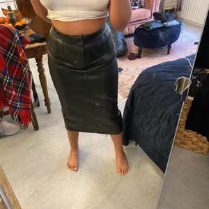 Zara kjol - Aldrig använd! Köpt för ca ett år sedan. Skinn kjol med mycket bra kvalite, man sätter fast den i en kedja på framsidan och även en knapp, den är lång och går ner till under knäna. nypris ca 600/700