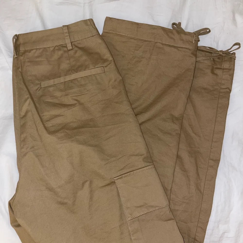 Bruna/beiga cargo pants från NA-KD. Använda fåtal gånger, nyskick. Byxorna sitter numera lite tight i midjan då de är i storlek 34 och jag har 36. . Jeans & Byxor.