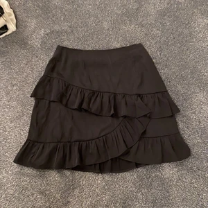 BIKBOK Kjol i satin med volanger  - Jättesöt svart kjol i satin med volanger. Storlek 38 men passar även 36. Aldrig använd! 