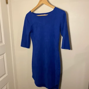 Mörkblå klänning i mocka  - En jättefin mörkblå klänning med tajt passform i mocka. Har en liten slits på vardera sida.