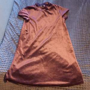 Ganska kort klänning i färg mörk lilla med glitter på. Den är kortärmad. Anven fåtal gånger. Storleken är 158/164