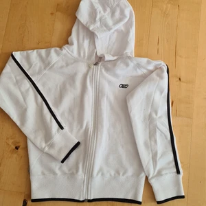Reebook luvtröja - Vit luvtröja från Reebook. Svarta revärer i mudd och ärmar och med dragkedja. Använd men i mycket gott skick. Strl 10. Pris 75kr