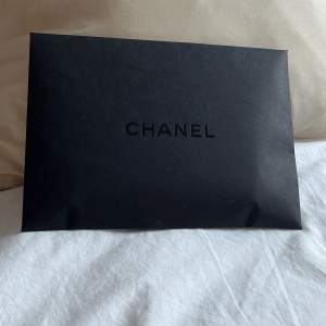 Svart kuvert med Chanel på, B 21,5 cm L 15,5 cm. Givetvis oanvänt.