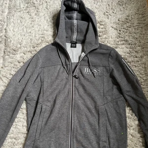 Hugo BOSS zip hoodie - Hugo BOSS zip hoodie i färgen grå. Storlek M men den sitter som S. Skick 9/10. Nypris ca 2000kr. Tror inte den finns att köpa ny längre.