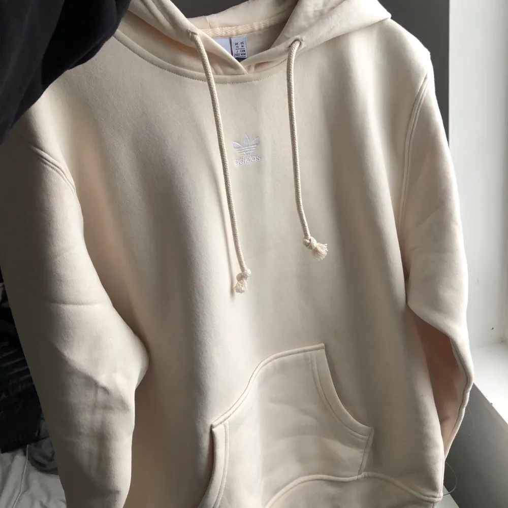 Krämvit Adidas hoodie, helt oanvänd i storlek L. Nypris 599kr Frakt 66 kr. Hoodies.