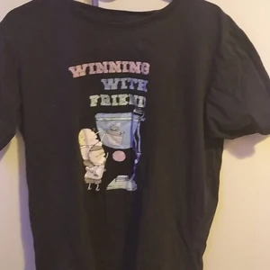 Winning with friends t shirt - En grå-svart t-shirt med texten "winning with friends" I storlek L fast uppskattas som M