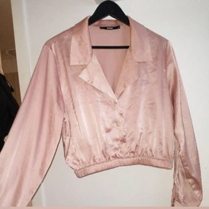 Rosa skjorta  - Fin rosa skjorta i glansigt tyg. Kort i midjan. Mycket fint skick och använd ett fåtal gånger. Finns I Göteborg