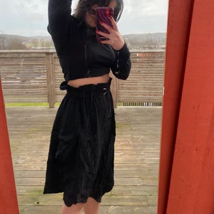 Svart långkjol  - Svart långkjol från Monki!🐒  Aldrig använd, endast testad för bilderna. Perfekt till vår och sommar samt har små detaljer som förhöjer outfiten. Två fickor på vardera sida och resår med volang i midjan. Dessutom ett inbyggt skärp och snedskuren nertill som skapar ett snyggt fall! 