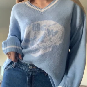 Ljusblå ”HCW” tröja - Fin ljusblå stickad tröja. Säljer pga passar inte min stil längre. Köpt i nyskick second hand, är inte äkta! HCW-inspirerad. Mjukt material, sticks inte! Superfin, oversize på mig som är S! Passar upp till L skulle jag tro!   Köparen står för frakten!