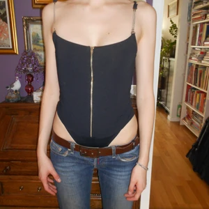 Stretchig svart y2k body 🕷️ - Cool genuin y2k body som jag ärvde av min mamma ❤️, passar storlek S och XS (med mindre byst). Har dessvärre tappat en av hängena (vänster sida), man kan dock ta bort en från andra sidan så blir det symmetriskt och påverkar ej passformen 😊 OBS om du köper mer än ett plagg är frakten gratis! 