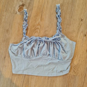 Blå topp - Cropped blått linne med en rosett vid bröstet. 