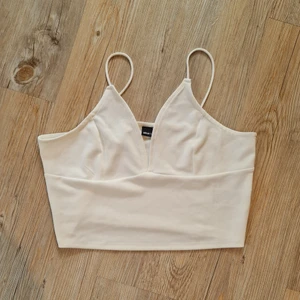 Vit topp - Vit croptop från Gina Tricot. Den har tunna axelband och är stretchig. 