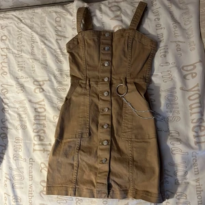 Klänning - En brun klänning som är jätte fin till sommaren. En kedja vid sidan, jätte fin den kommer aldrig till använding nästan aldrig använd!