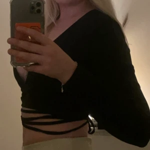 Svart topp med snörning  - Skitsnygg topp med snörning som du kan knyta hur du vill. Sitter skit snyggt på.