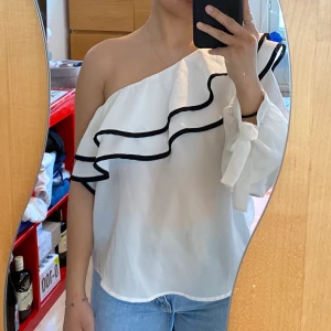 Vit one shoulder blus - En axlad vit blus med svarta detaljer, använd endast en gång