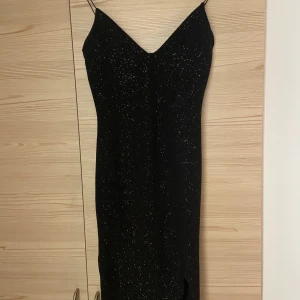 Svart klänning från Nelly  - Svart glitter klänning från Nelly med rush där bak o en slit på framsida