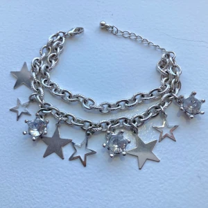 Nytt silverarmband med stjärnor och berlocker - Fint silvrigt armband med berlocker. Nyskick då jag fick det i julklapp men använder aldrig armband så bättre att någon annan gör det! 😊 känns ganska tungt och inte billigt eller plastigt. 