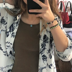 Vit blus med blått mönster - Söt vit blus med blått tryck. Köpt second hand men bra skick❤️‍🔥❤️‍🔥passar S-M👛👛👛👛köpare står för frakt