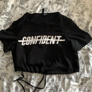 Svart  T-shirt med tryck  - Säljer denhär fina cropade svarta T ä-shirten💕Det är ett tunt material och trycker är helt✨ den ser knappt använd ut och är i mycket bra skick☺️💕