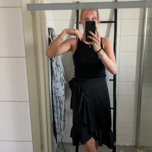 Svart satin omlott volangkjol - Svart satin omlott volangkjol med knytning. Den är medel lång går till knät. Kommer från butiken Chelsea i Göteborg. Storleken är ondsinte men passar dem allra flesta då du kan reglera själv med bandet. Inte använd jätte mycket. Priset kan alltid diskuteras. Betalning sker alltid innan jag skickar. + frakt tillkommer ❤️🤪🧚🏼‍♀️