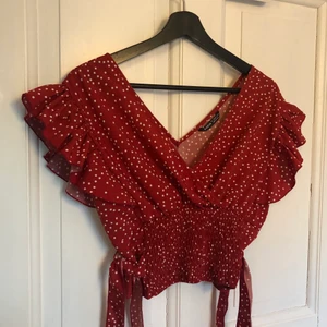 Rödprickig Blus/Top Shein  - Supersöt rödprickig topp/blus från Shein med knyte på båda sidorna i midjan. Aldrig använd så i fint skick! Den är i storlek L men funkar på en S/M också. Köparen står för frakt! 
