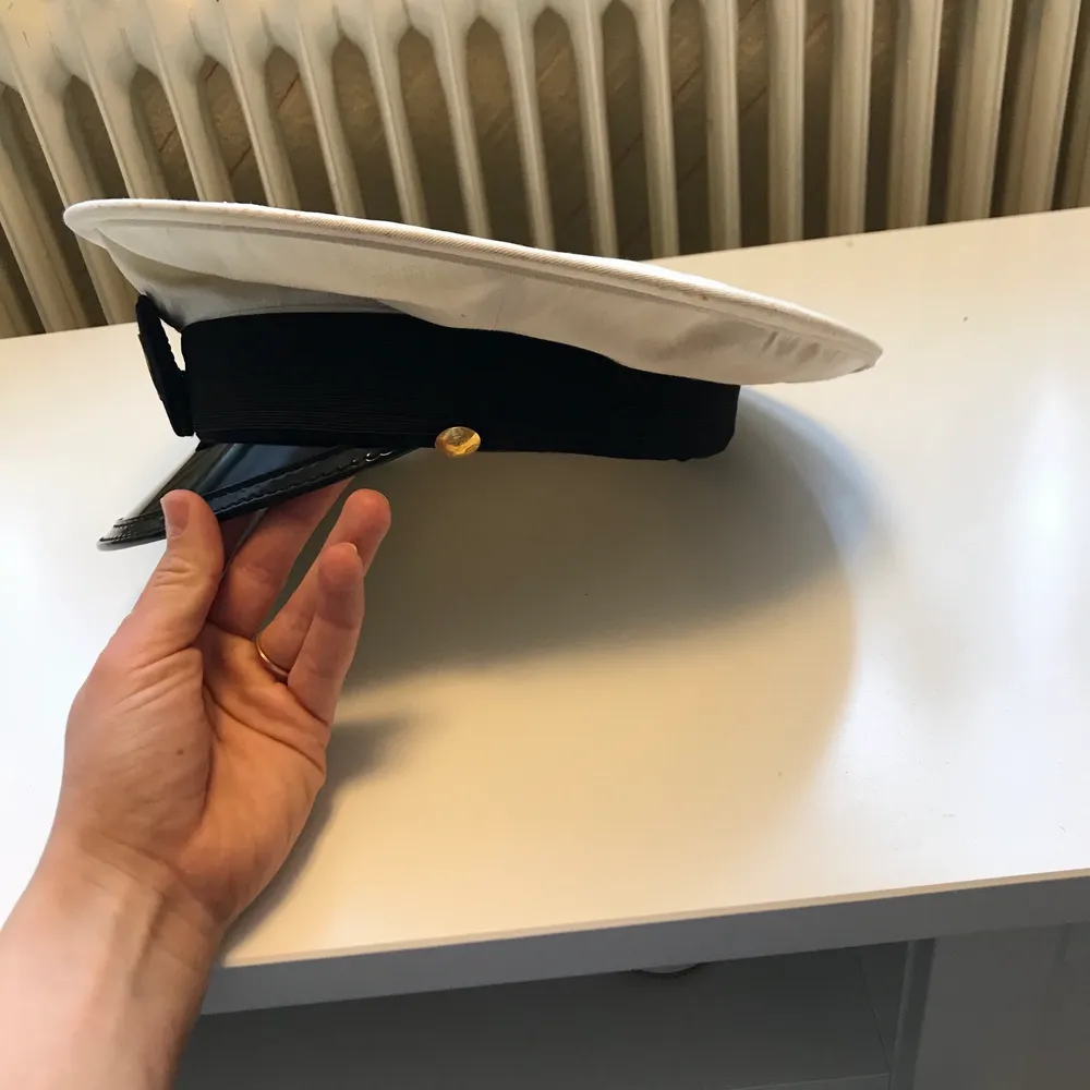 Säljer en hatt jag köpte från en antikloppis i Vimmerby förra sommaren. Min bästa gissning är att hatten är ifrån musikkåren Lyran. Det vita tyget är fläckat på sina ställen, men jag tvättade tyget med diskmedel, varmt vatten och lite vittvättmedel när jag köpte den vilket tog bort det mesta. Hatten är liten, 17 cm i diameter så om man vill bära den kan det vara bra att veta. Kan skickas, köparen betalar frakten.. Asusteet.