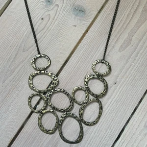 Halsband med stora ovala länkar i antikguld - Säljer ett statement-halsband med stora, oregelbundna ovala länkar i antikguld. Kedjan är mörk och länkarna har en hamrad, rustik yta som ger en cool och unik look. Perfekt för att lyfta vilken outfit som helst.
