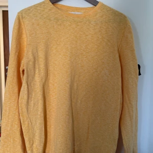 Stone Island tröja  - Tröja från Stone Island med rund halsringning och lång ärm. Tröjan har en klassisk passform och den ikoniska Stone Island-loggan på ärmen. Härlig nu till sommarn! 