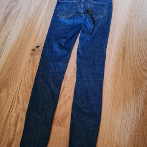 Mörkblå skinny jeans Molly från Gina Tricot - Mörkblå skinny jeans från Gina Tricot, modell Molly. Jeansen har klassisk femficksdesign, hög midja och är tillverkade i stretchig bomullsblandning för en bekväm passform.. Använda enstaka gång. Jag ser inget att anmärka på utom att blå färg från jeansen har kommit på lapparna vid tvätt 