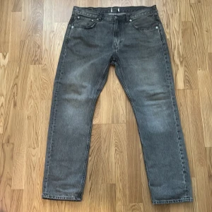 Grå raka jeans - Säljer ett par grå jeans med rak passform och klassisk femficksdesign. Jeansen har normal midja och subtil tvätt för en avslappnad look. Perfekta till vardags för en stilren och enkel outfit.