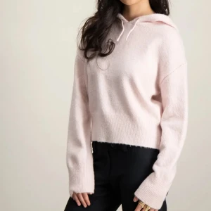 Ljusrosa stickad hoodie - Mysig ljusrosa stickad hoodie med croppad passform och långa ärmar. Tröjan har en stor huva och breda ribbade muddar vid ärmslut och nederkant. Perfekt för en avslappnad och trendig stil. Köpt på Gina Young i storlek: 170 men skulle säga att den är Xs-S (nyskick, använd en gång)