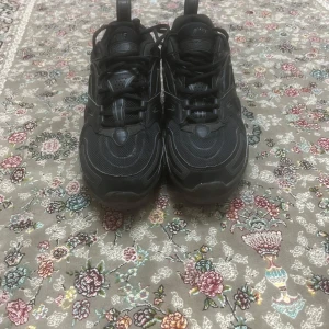 Svarta Nike Air Vapormax sneakers - Säljer ett par helsvarta Nike Air Vapormax sneakers med tydlig Nike-logga på sidan. Skorna har snörning, rund tå och en unik, bubblig sula som ger en sportig look. Perfekta för dig som gillar streetwear och vill ha något bekvämt och stilrent.(Den har inga skosulor)