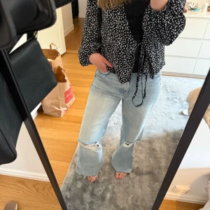 Ljusblå jeans med bootcut - Säljer ett par ljusblå jeans med bootcut och slitningar vid knäna. Jeansen har klassisk femficksdesign. 