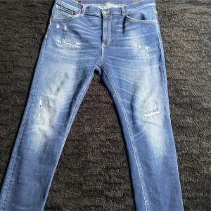 Blå superskinny jeans Alex - blå jeans från dondup  med slitna detaljer och klassisk femficksdesign. Jeansen har en tight passform och är tillverkade i stretchigt denimtyg för extra komfort. Perfekta för dig som gillar en smal siluett och modern look.