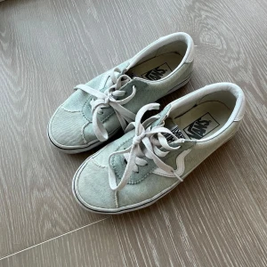 Ljusgröna vans - Säljer ett par ljusgröna Vans sneakers med vita snören och vit sula. Klassisk låg modell med rund tå och platt sula. Perfekta för en avslappnad stil.