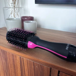 Varmluftsborste från Revlon - En svart och rosa varmluftsborste från Revlon med ovala borsthuvud och täta borststrån. Perfekt för att styla och torka håret samtidigt. Ergonomiskt handtag och snygg design. Använd fåtal gånger  