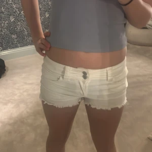 Vita lowaiste jeansshorts - Säljer ett par vita, lågmidjade jeansshorts med fransig kant. Shortsen är en gamal h&m vara. Jag har storlek xs och kan ha på mig dom bra🥰