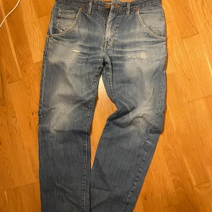 Blå jeansbyxor med slitningar - Blå jeans, lätt slitna detaljer och raka ben. Mått på bilderna.