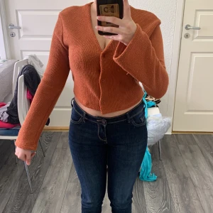 Rostfärgad croppad kofta från SHEIN - Säljer en rostfärgad croppad kofta från SHEIN med v-ringning och vida ärmar. Tröjan är stickad och har knappar framtill. Perfekt för dig som gillar trendiga och bekväma plagg.