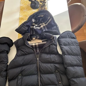 Burberry jacka - Blå burberry dunjacka som kan bli en väst så jackan funkar för sommaren samt vintern. Köpte jackan i Italien 2022 för cirka 10 tusen men nypris är runt 13-14 tusen. Jackan är sparsamt använd och säljes då jag inte har någon användning för jackan, pris kan diskuteras och jackan är självklart äkta, har inte kvitto kvar men skulle de va några mer funderingar är det bara att höra av sig.