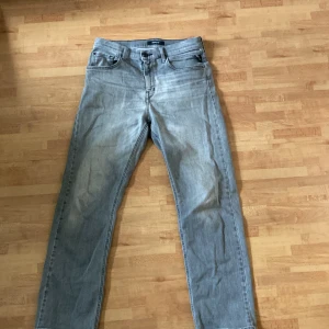 Gråa jeans från Replay - Säljer ett par ljusblå jeans från Replay med klassisk femficksdesign och raka ben. Jeansen har snygga detaljer på bakfickorna och stängs med dragkedja och knapp. Perfekta för en avslappnad stil.                              Modell Thad, priset är ej hugget i sten. Skriv vid minsta lilla fråga!
