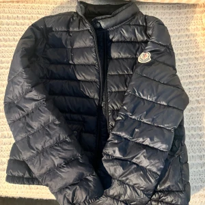 Äkta Moncler vår/sommar dunjacka  - Säljer en dunjacka från Moncler med klassisk quiltad design. Jackan har dragkedja framtill, lång ärm och Moncler-logga på ärmen. Perfekt för kyligare dagar och riktigt snygg till jeans. Kan sänka pris vid snabb affär!!!🩷🩷
