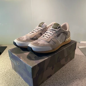 Valentino Rockrunner sneakers beige/camo - Säljer nu dessa feta valentino rockrunners! Säljer dom för att jag inte använder de längre. Skorna är i bra skick utan några skavanker. Lite smuts här o där men inget man märker från avstånd! Allt og ingår dvs nya snören, visitkort, dustbag och låda. Hör av er vid fler frågor!